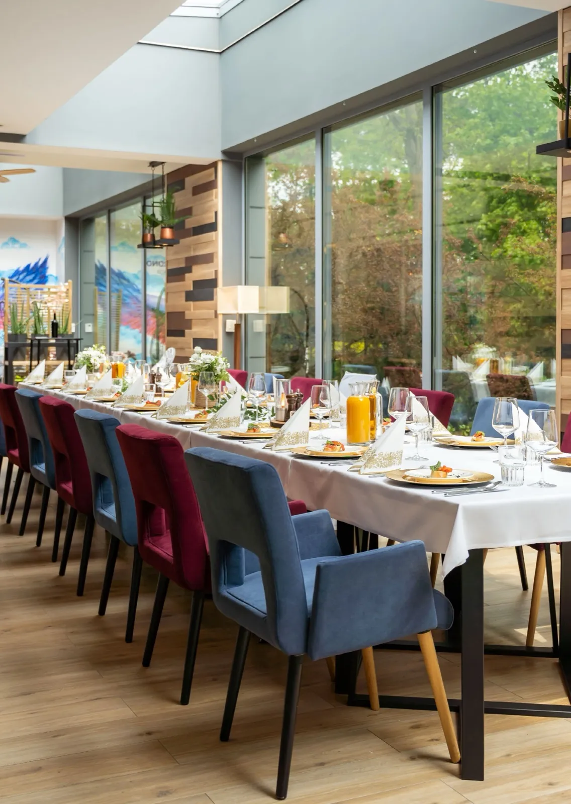Jasna sala restauracyjna z długim stołem bankietowym przy panoramicznych oknach