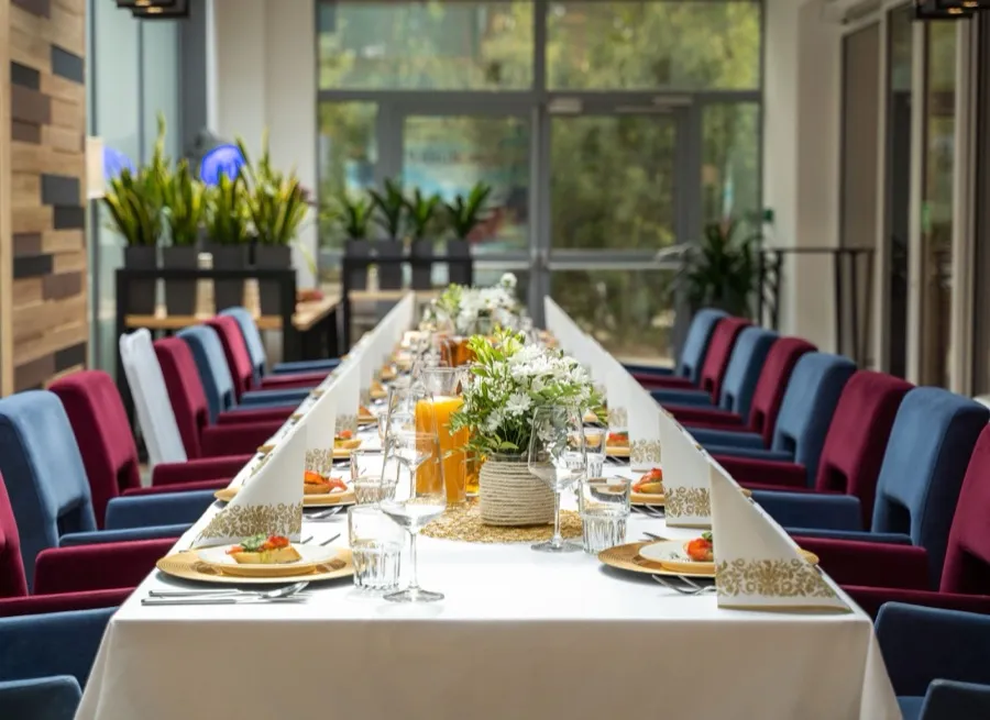 Jasna sala restauracyjna z długim stołem bankietowym przy panoramicznych oknach